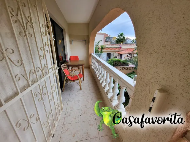 BookNoFees: ubytování, Buen Paso, Tenerife, Španělsko – Balkon se stolem, červenými židlemi a výhledem na střechy a palmy