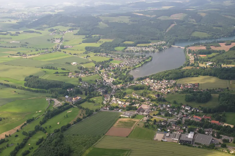 Jezero Sorpesee z ptačí perspektivy, s vesnicí Amecke na jeho východním břehu a zalesněnými kopci Sauerlandu v okolí