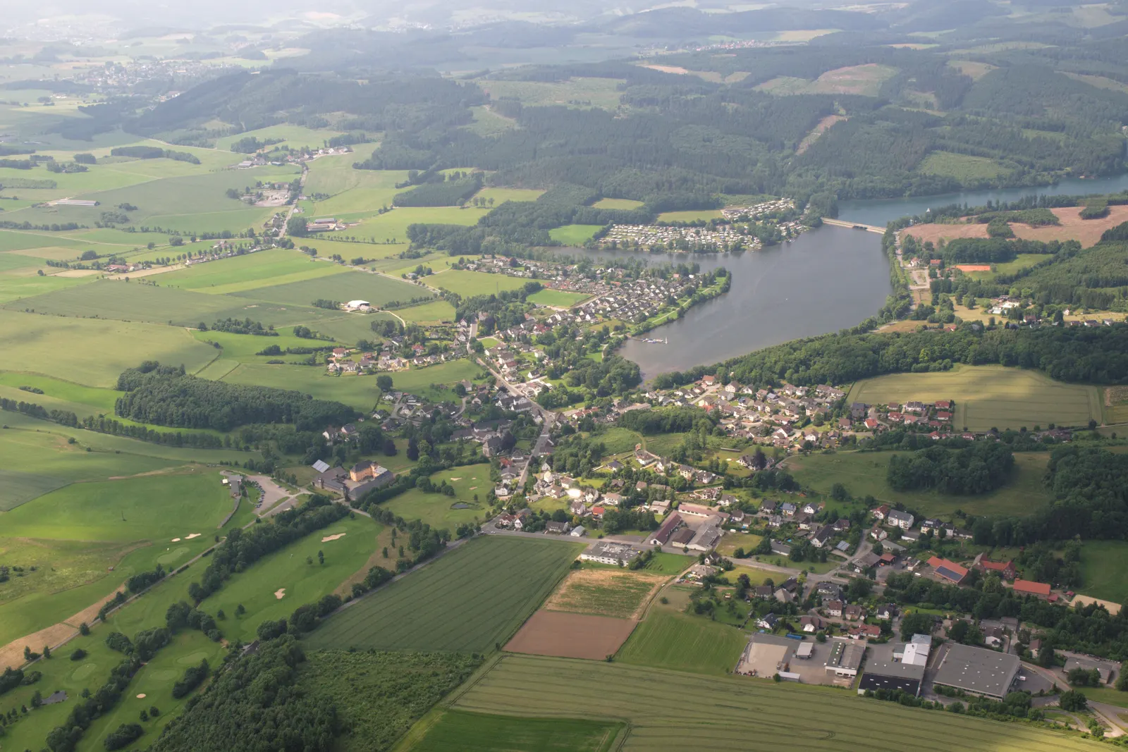 Jezero Sorpesee z ptačí perspektivy, s vesnicí Amecke na jeho východním břehu a zalesněnými kopci Sauerlandu v okolí