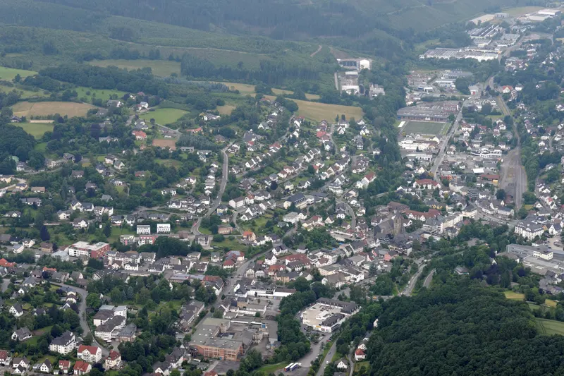 Město Sundern z ptačí perspektivy, domy podél údolí Röhr mezi zalesněnými kopci